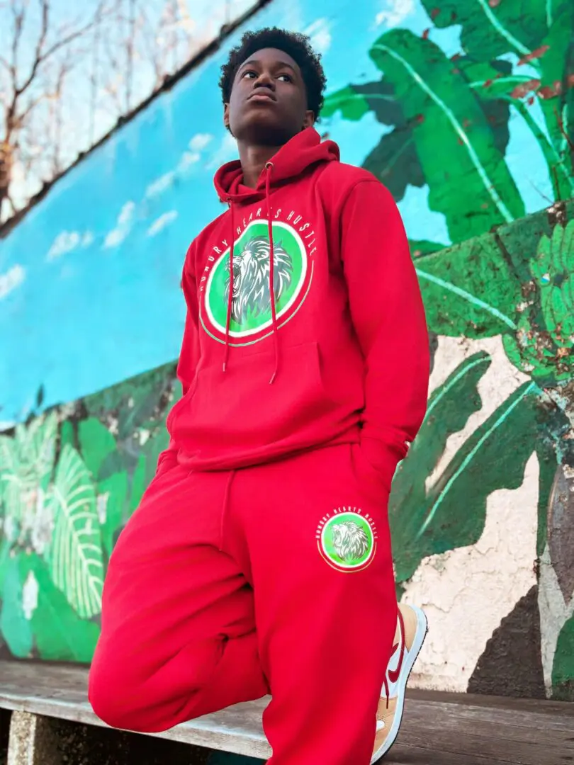 A man in red and green outfit standing next to a wall.