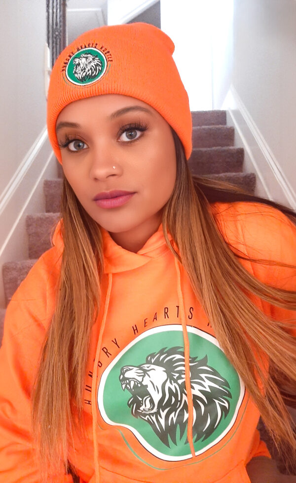 A woman in an orange hoodie and hat.